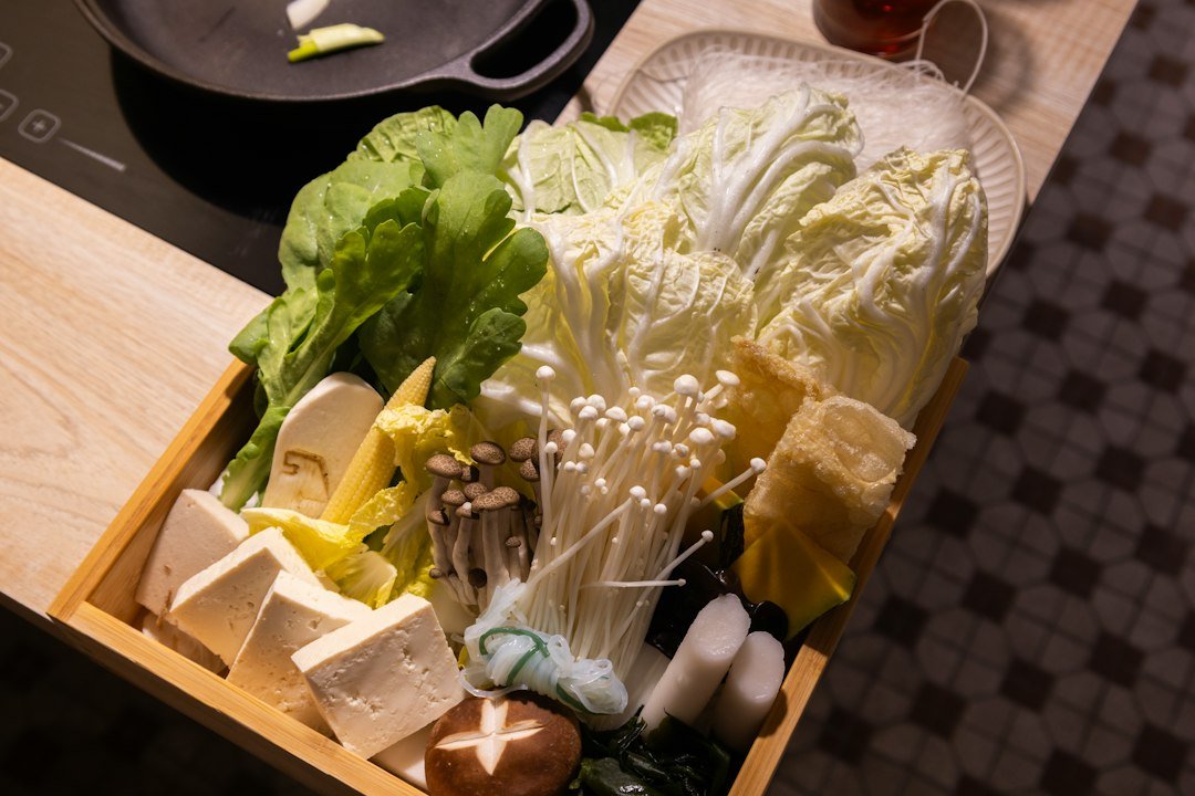 Fresh vegetables and tofu arranged in a wooden tray